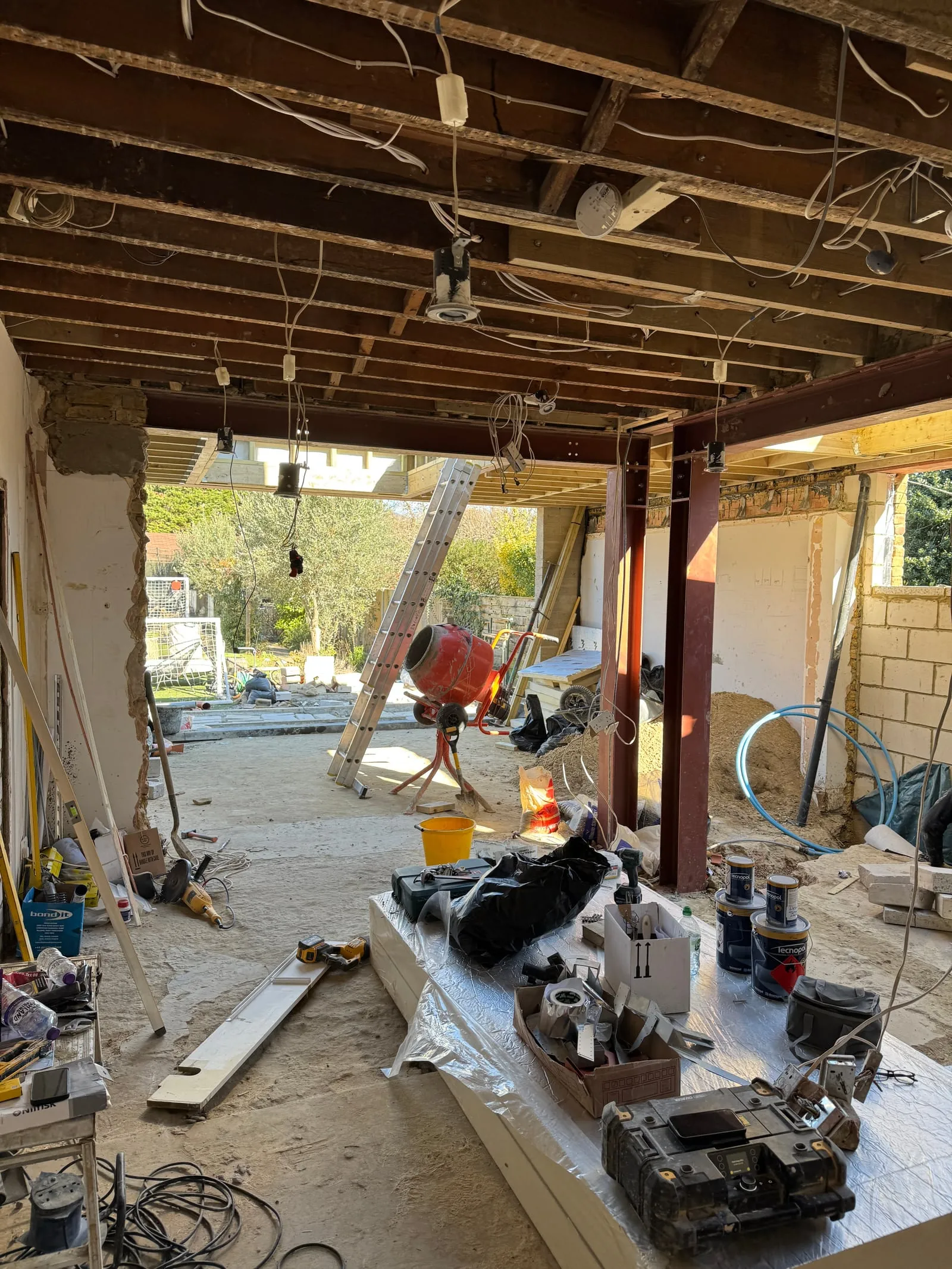 First-fix ceiling timbers with cement mixer visible through the opening