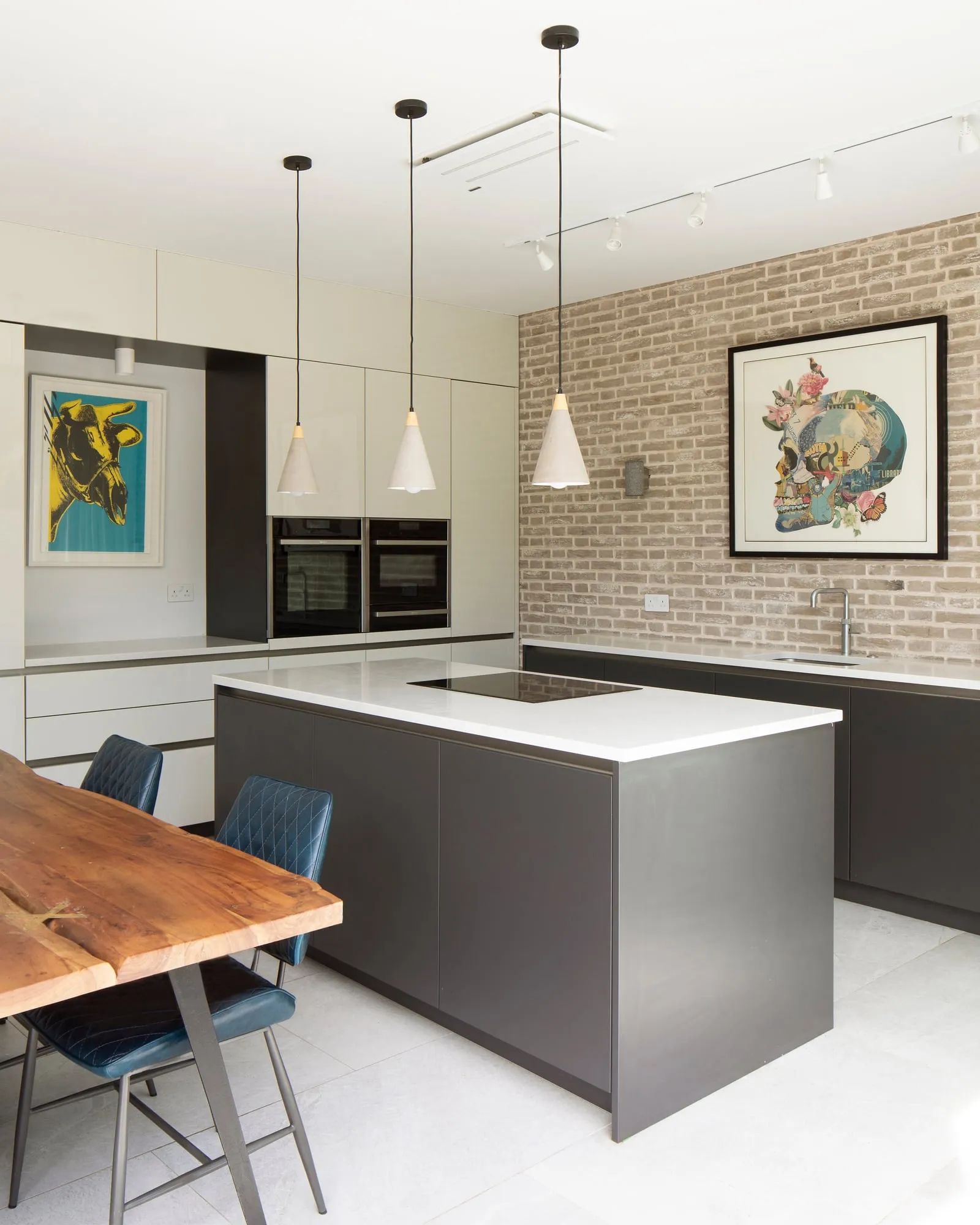 Open-plan kitchen island with pendant lighting and exposed brick wall